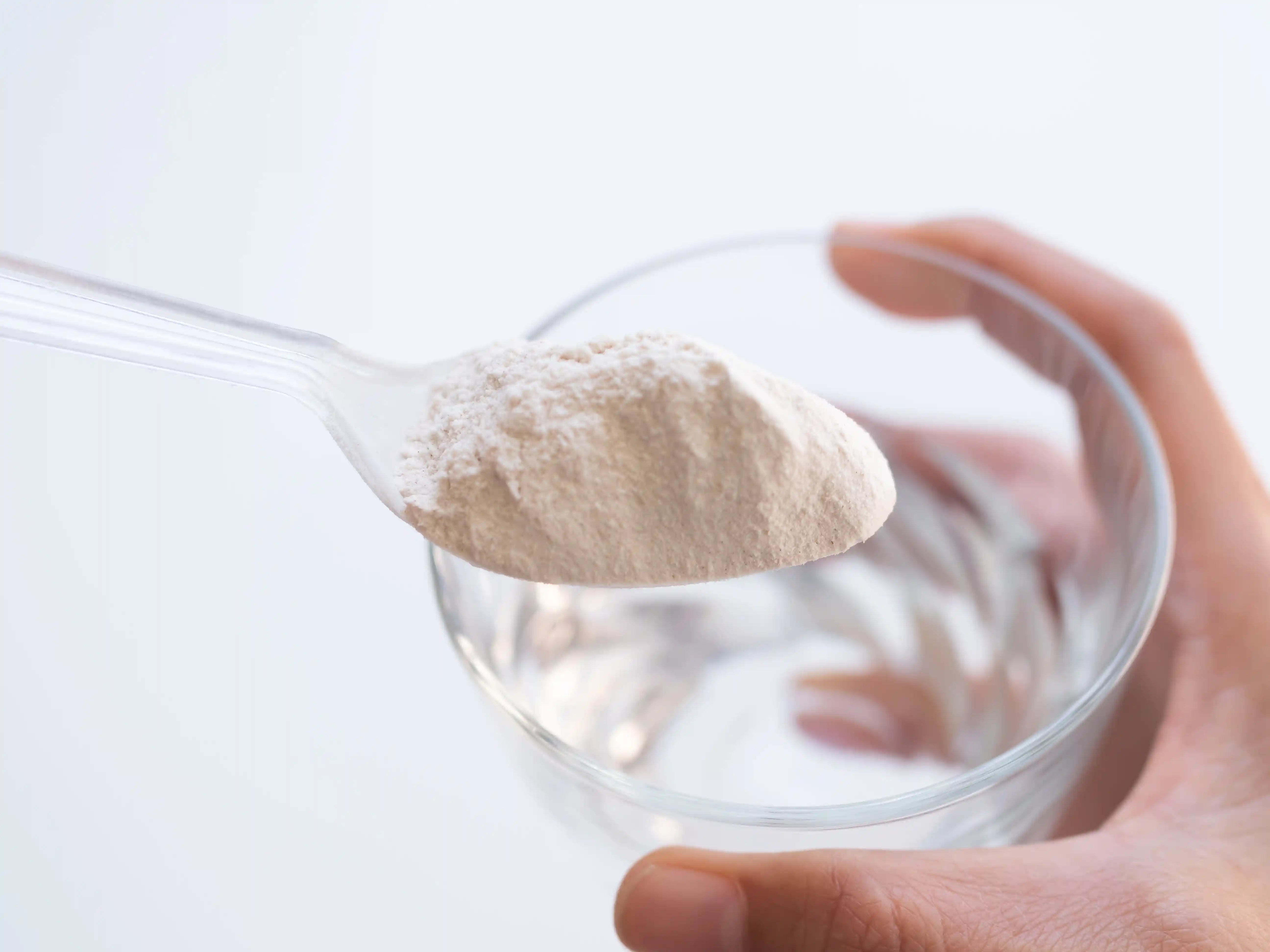spoonful of collagen powder over a glass of water