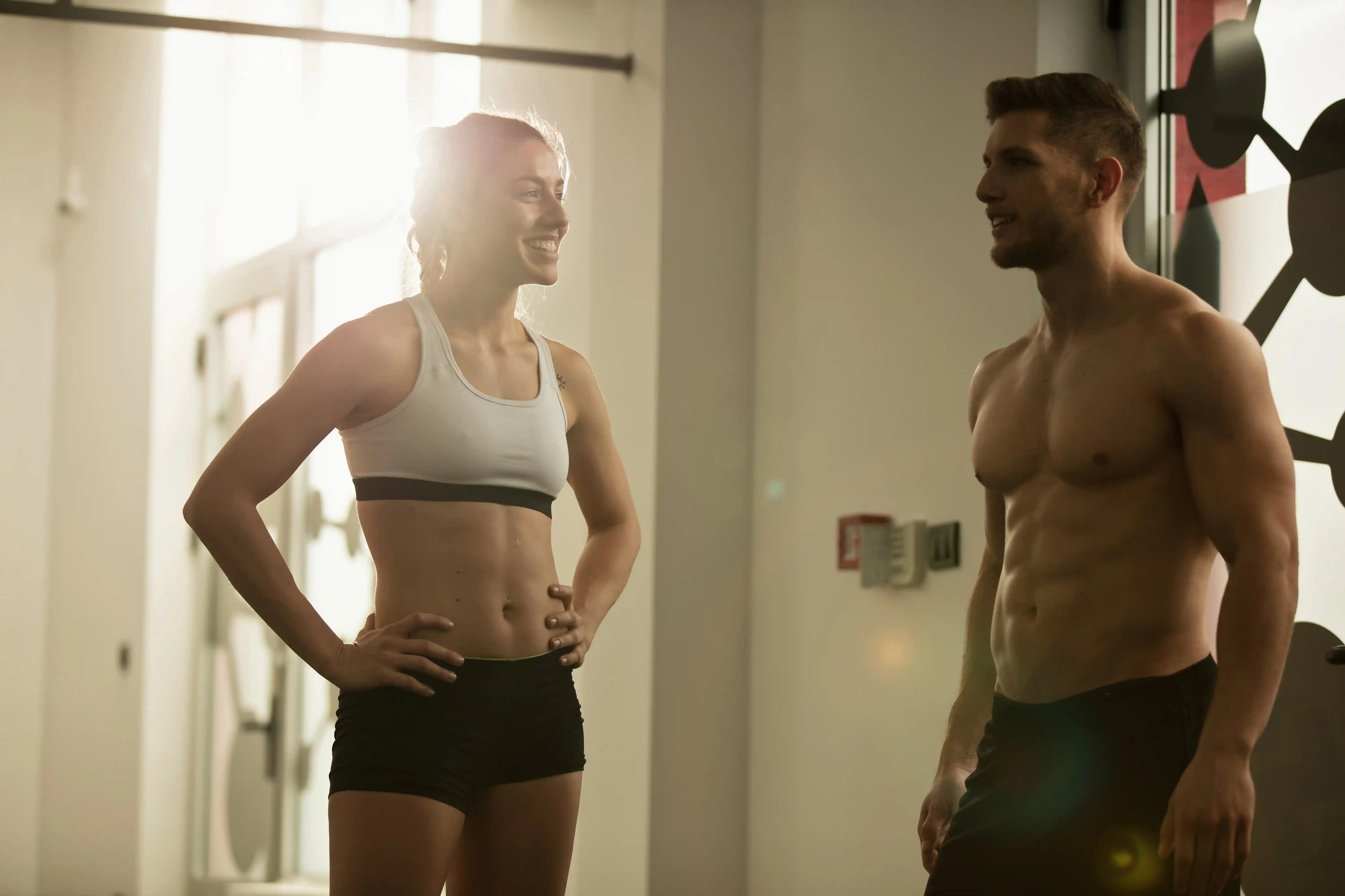 lean man and woman in the gym smiling at eachother